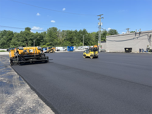 Asphalt Care Inc crew laying fresh pavement in a commercial parking lot